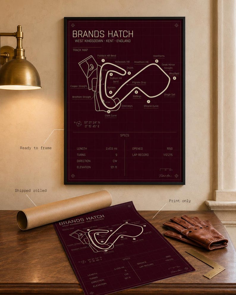 May include: A framed burgundy print of the Brands Hatch race track in West Kingsdown, Kent, England. The track map is in white, with text including track details and specs. A rolled print and leather gloves are also visible.
