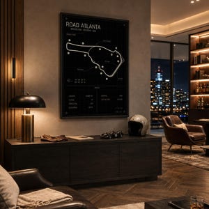 May include: A framed black and white print of the Road Atlanta racetrack map hangs above a dark wood cabinet. A vintage racing helmet and a model race car sit on the cabinet. A lamp with a gold base and black shade is on the left.