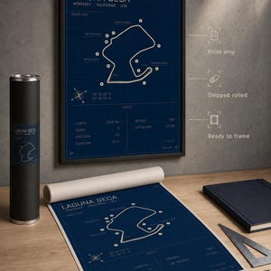 May include: A framed Laguna Seca track map print in a black frame, with a rolled print and a cylindrical container. The map is white on a navy blue background, with track details and specifications. The print is ready to frame.