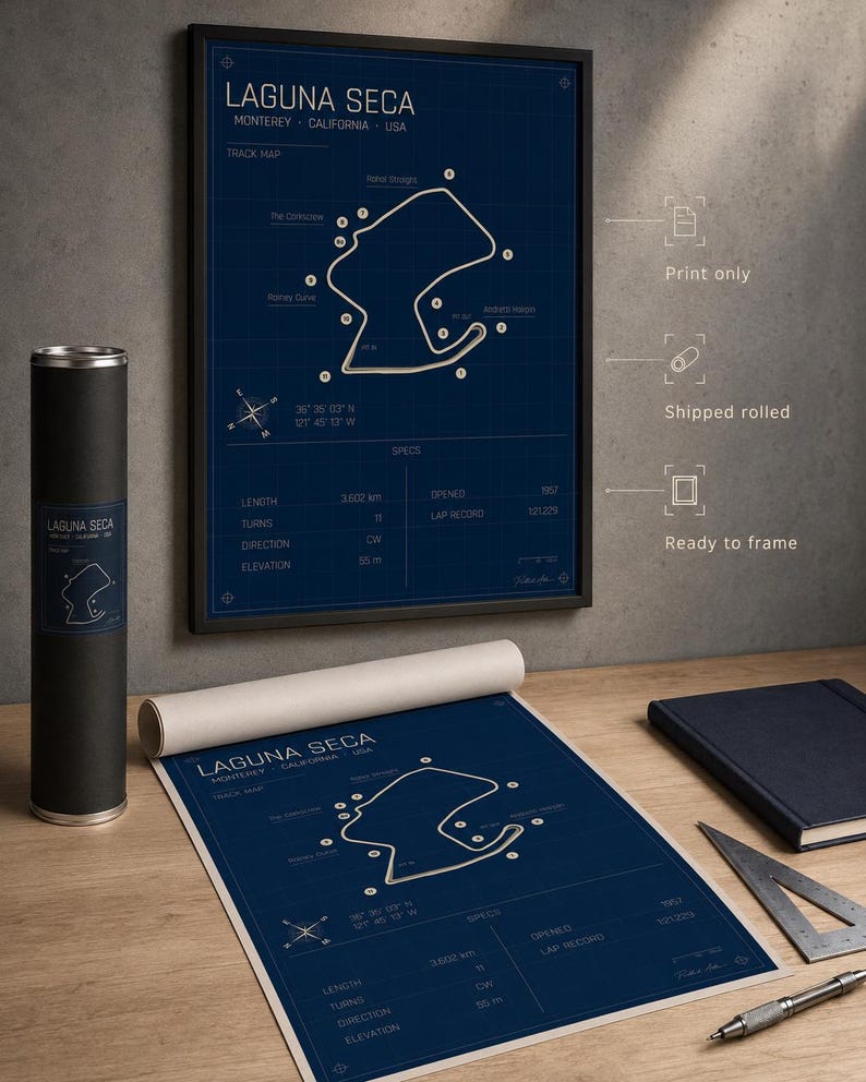 May include: A framed Laguna Seca track map print in a black frame, with a rolled print and a cylindrical container. The map is white on a navy blue background, with track details and specifications. The print is ready to frame.
