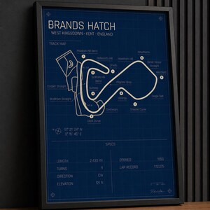 May include: Framed Brands Hatch track map print. The blueprint-style design features the track layout, labeled turns, and specifications. The print includes the track's length of 2.433 miles and elevation of 121 feet.