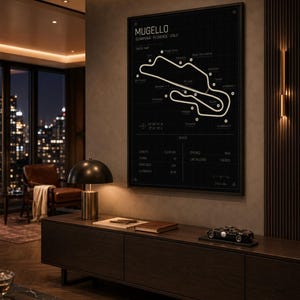 May include: A framed black and white track map of the Mugello circuit in Italy. The poster includes track details and is displayed above a dark wood cabinet. A small model race car sits on the cabinet.