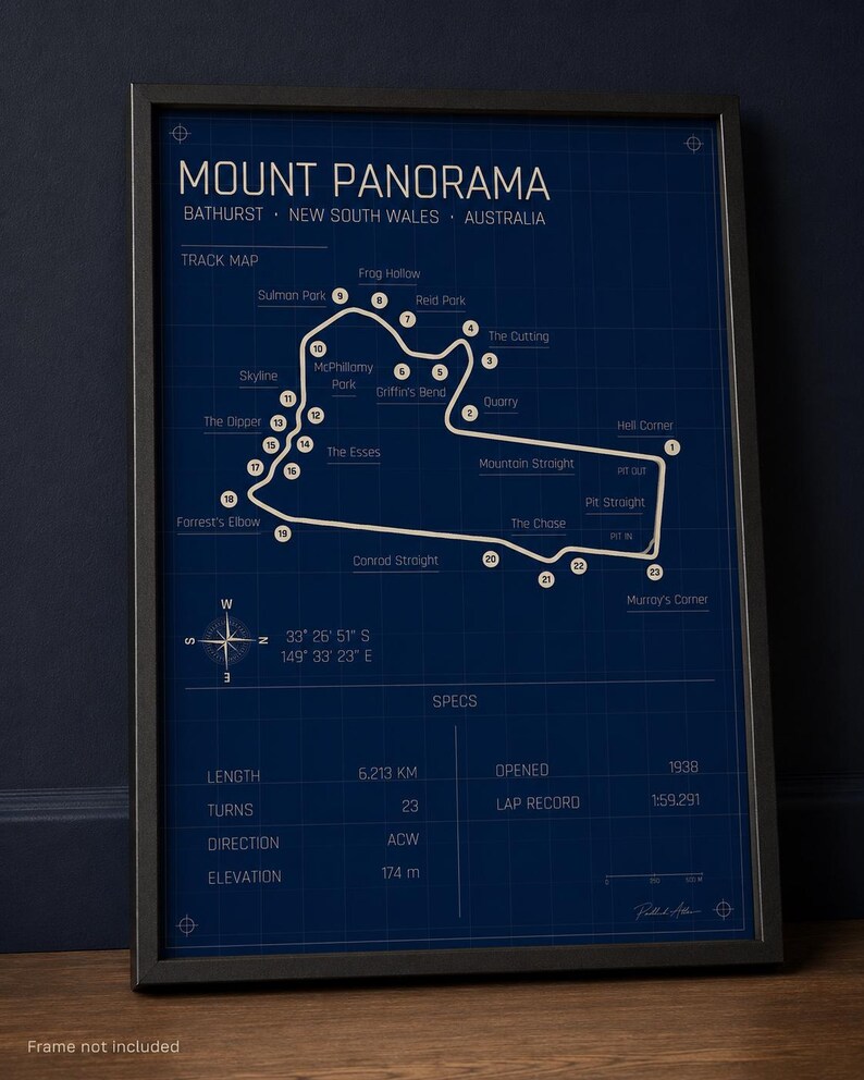 May include: A framed Mount Panorama track map poster. The dark blue print features the track layout with labeled turns and key locations. Includes specs: 6.213 km length, 23 turns, and opened in 1938. The frame is black.