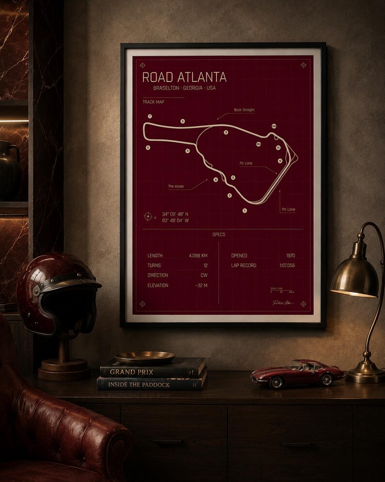 May include: A framed print of the Road Atlanta race track in Braselton, Georgia, USA. The track map is in white on a burgundy background. The print includes track specifications and is displayed with a vintage helmet, books, and a model car.