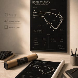 May include: A black and white print of the Road Atlanta race track map. The print includes track details, coordinates, and specifications. A rolled print and a framed version are displayed on a desk with a pen holder, notebook, and gloves.