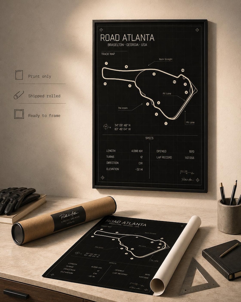 May include: A black and white print of the Road Atlanta race track map. The print includes track details, coordinates, and specifications. A rolled print and a framed version are displayed on a desk with a pen holder, notebook, and gloves.