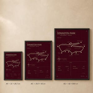 Op de afbeelding: Drie ingelijste prints van de Donington Park racecircuitkaart in bordeauxrood. De prints zijn in A4 (21 x 29,7 cm), A3 (29,7 x 42 cm) en A2 (42 x 59,4 cm) formaten. Elke print heeft een zwarte lijst en witte tekst.