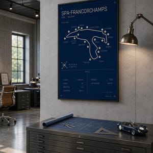 Pode incluir: Uma planta emoldurada do circuito de Spa-Francorchamps na B&eacute;lgica. O mapa da pista &eacute; branco sobre um fundo azul, com o texto "SPA-FRANCORCHAMPS" no topo. Um pequeno carro de brinquedo azul est&aacute; em um arm&aacute;rio de metal.