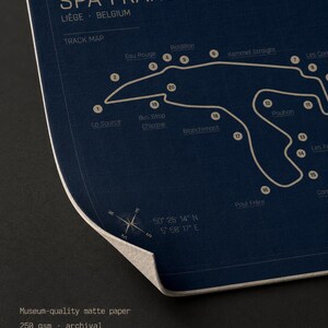Pode incluir: Um mapa de pista azul escuro do circuito de Spa-Francorchamps em Li&egrave;ge, B&eacute;lgica. O mapa apresenta um contorno branco da pista com curvas rotuladas e o texto "TRACK MAP". O papel &eacute; fosco e de arquivo com qualidade de museu.