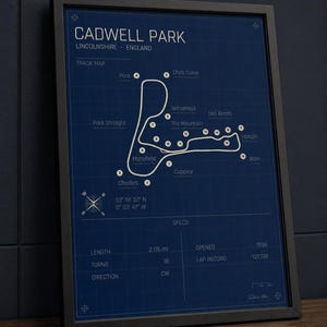 K&ouml;nnte beinhalten: Gerahmter Druck der Rennstrecke Cadwell Park in Lincolnshire, England. Die Streckenkarte ist wei&szlig; auf dunkelblauem Hintergrund, mit Beschriftungen f&uuml;r Kurven und Merkmale. Der Druck enth&auml;lt Spezifikationen wie L&auml;nge (3,5 km) und Er&ouml;ffnungsjahr (1938).