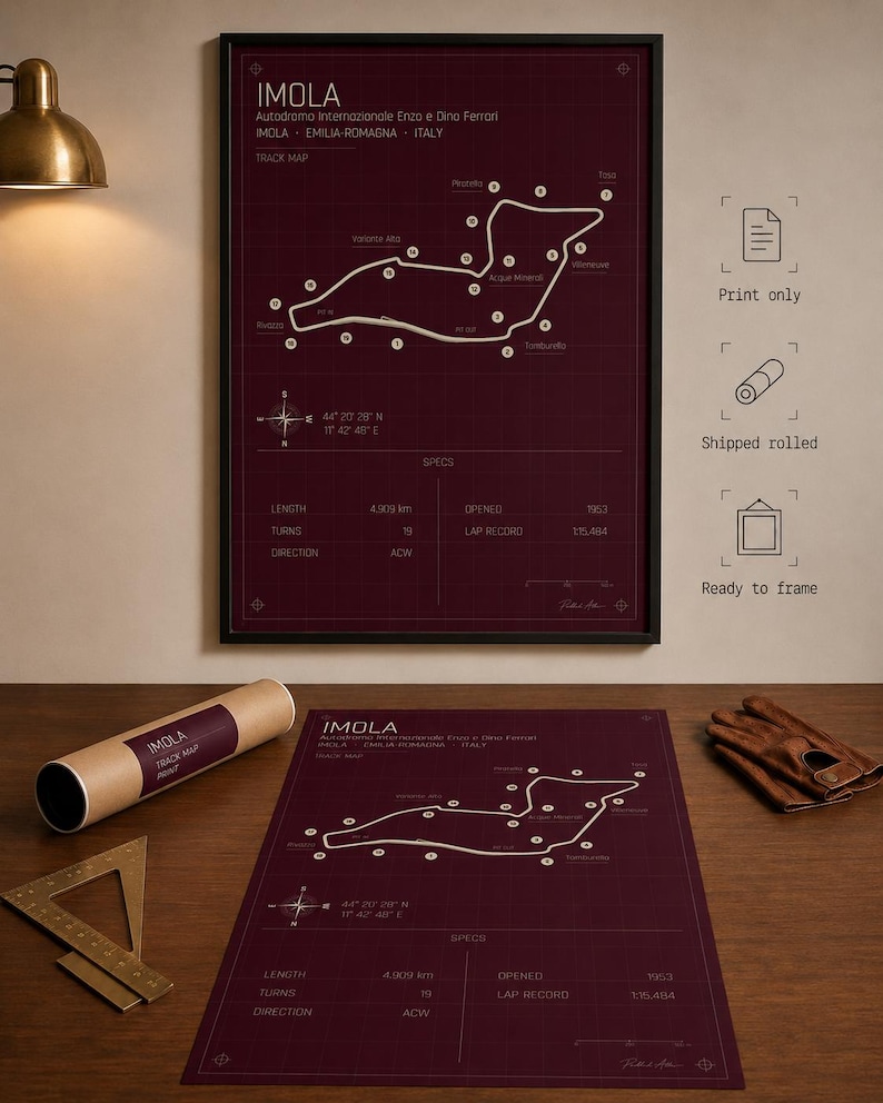 May include: A framed burgundy print of the Imola race track map, with the text "IMOLA" and track details. A rolled print and a print on a table are also visible. The map shows the track layout, with specs including length of 4.909 km.