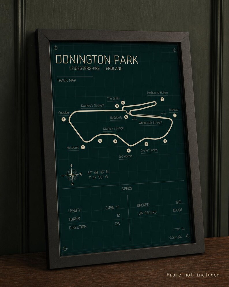 Op de afbeelding: Ingelijste print van het Donington Park circuit in Leicestershire, Engeland. De kaart is wit op een donkergroene achtergrond. Inclusief details zoals lengte, bochten en ronderecord. De lijst is zwart.