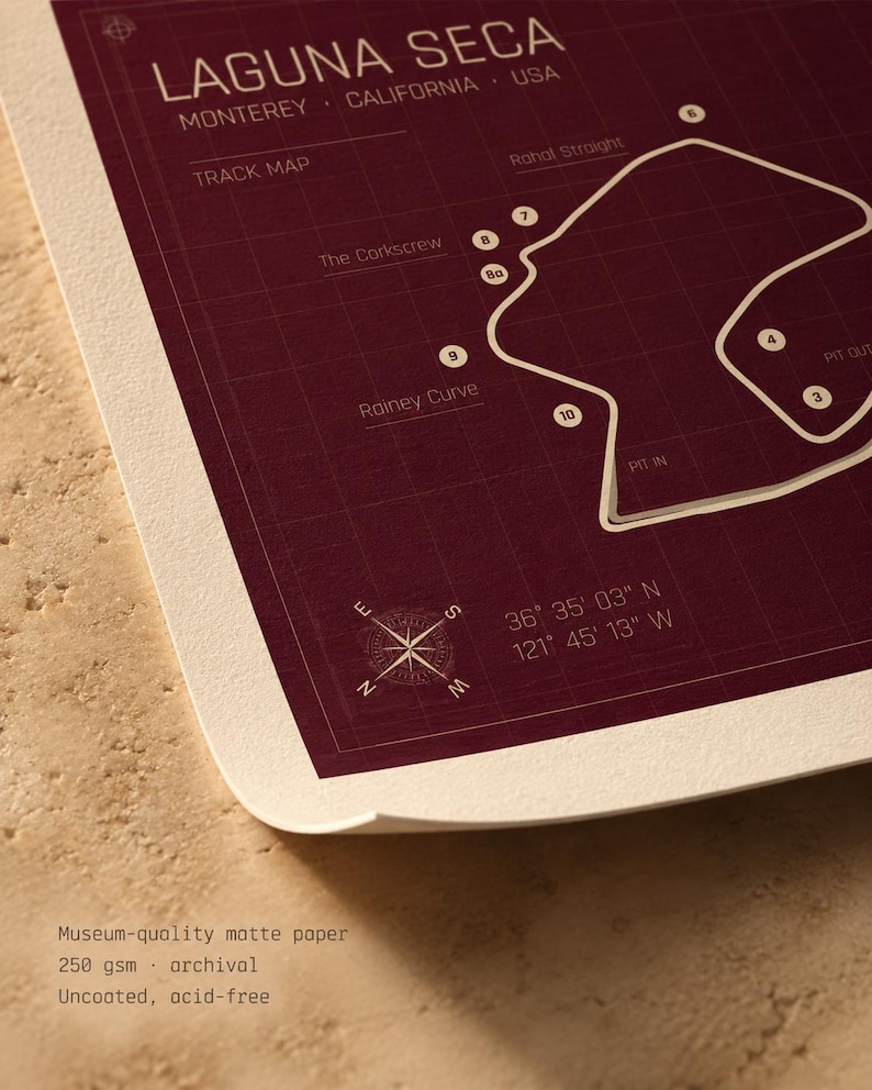 May include: A maroon and white track map print of Laguna Seca, California. The print includes the track layout, labeled features like "The Corkscrew" and "Rainey Curve", and coordinates. The paper is museum-quality matte, 250 gsm, archival, and acid-free.