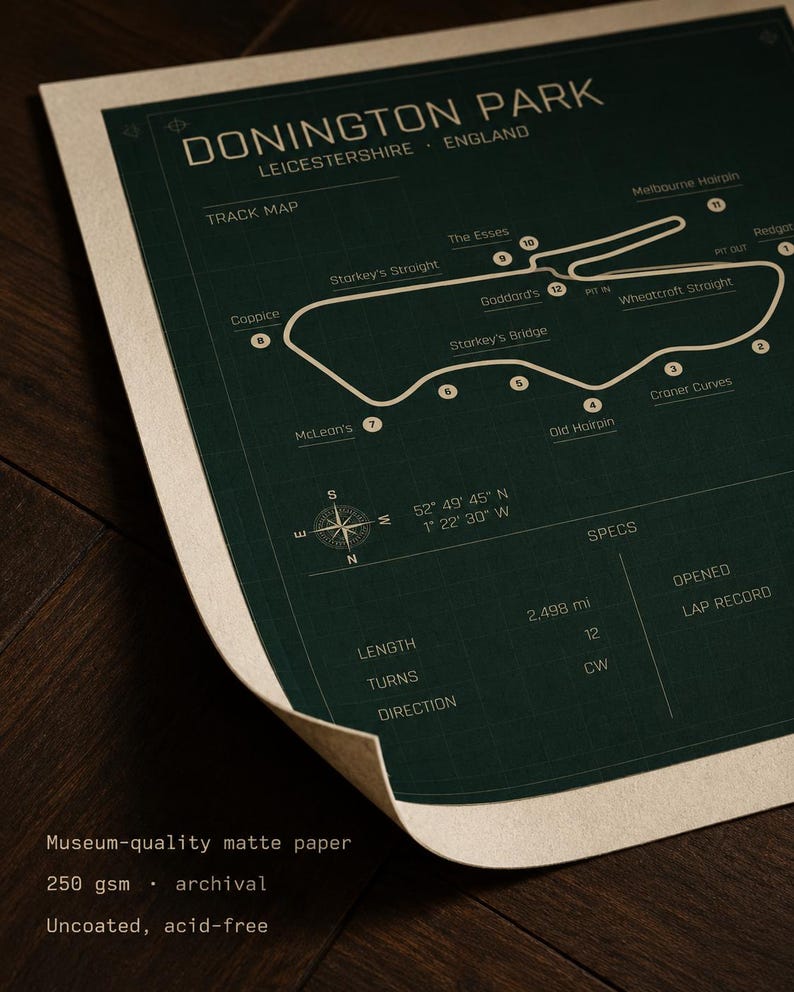 Op de afbeelding: Een donkergroene print van het Donington Park circuit in Leicestershire, Engeland. De circuitkaart bevat gelabelde bochten en een kompasroos. De print bevat ook specificaties zoals lengte en bochten. De tekst "Museum-quality matte paper" is zichtbaar.