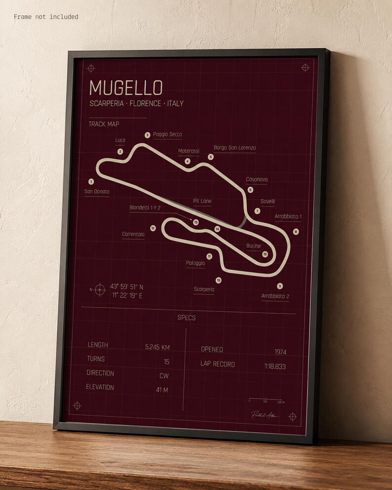 May include: A framed print of the Mugello race track in Italy. The track map is white on a burgundy background, with the track's name and specifications. The frame is black.