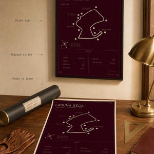 May include: A framed burgundy print of the Laguna Seca racetrack map. The print includes track details and specifications. A rolled print and a pair of driving gloves are on a wooden surface. The print is ready to frame.
