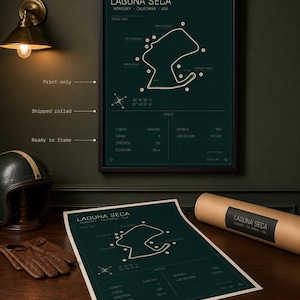 May include: A framed Laguna Seca race track map print in a dark green and white design. The print includes track details and is displayed with a rolled print and a vintage helmet and gloves.