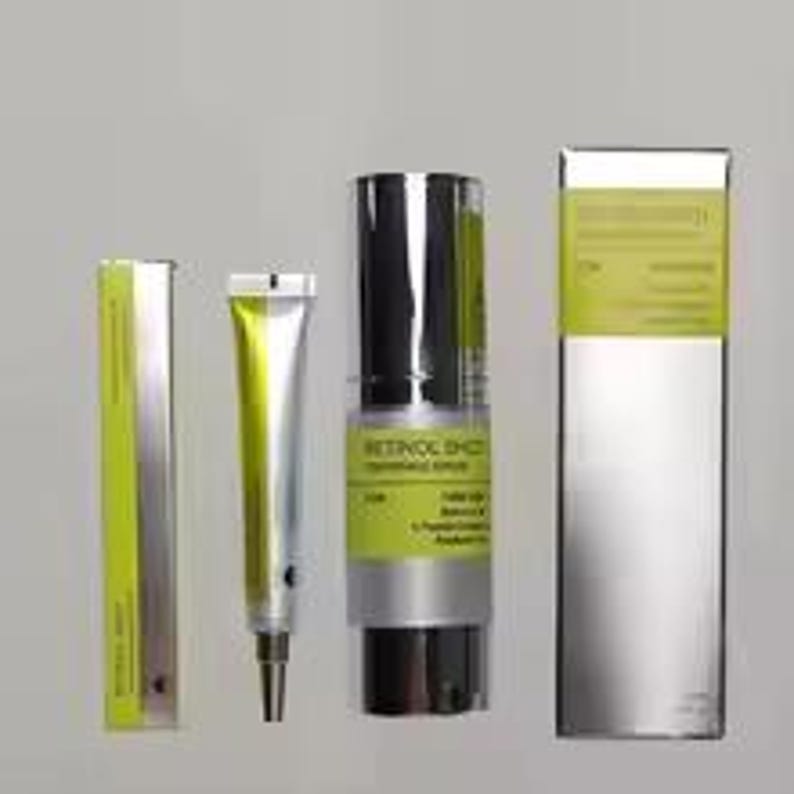 May include: A Retinol Shot skincare set featuring a silver and lime green tube, a matching silver and lime green pump bottle, and two corresponding rectangular silver and lime green boxes. The text on the packaging reads Retinol Shot.