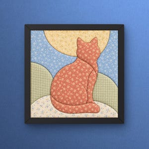 May include: A square framed fabric wall art piece featuring a patchwork cat silhouette in a floral coral pattern. The background consists of a yellow sun, blue floral sky, and green checkered hills, all crafted from various patterned textiles.