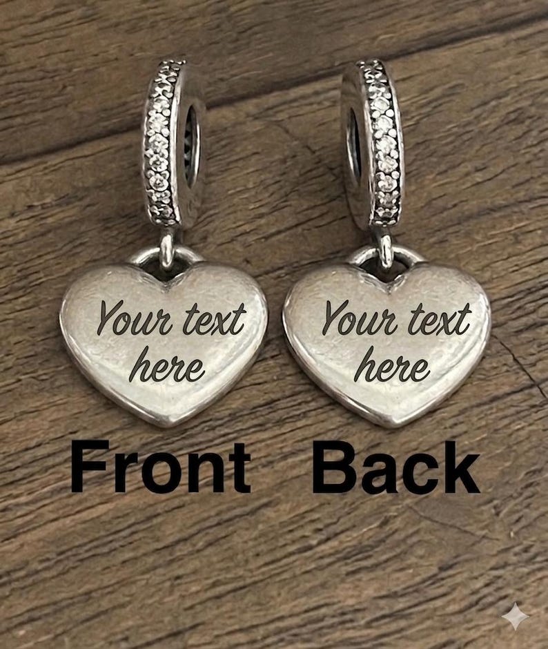 K&ouml;nnte beinhalten: Zwei silberfarbene herzf&ouml;rmige Anh&auml;nger mit einer &Ouml;se, die mit klaren Steinen besetzt ist. Jeder Anh&auml;nger ist mit dem Text 'Your text here' graviert. Das Bild enth&auml;lt die Beschriftungen 'Front' und 'Back' zur Kennzeichnung der Ausrichtung.