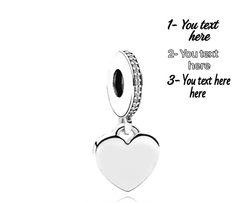 K&ouml;nnte beinhalten: Ein silberfarbener herzf&ouml;rmiger Anh&auml;nger mit einer runden &Ouml;se, die mit einer Reihe klarer Steine besetzt ist. Rechts steht der Text: 1- You text here, 2- You text here, 3- You text here. Der Anh&auml;nger hat eine glatte, polierte Oberfl&auml;che.