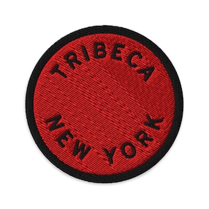 May include: A circular embroidered patch featuring a vibrant red background with a thick black border. The text TRIBECA is stitched in black along the top curve, and the text NEW YORK is stitched in black along the bottom curve of the patch.