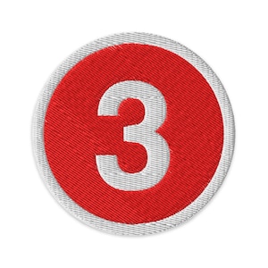 May include: Embroidered patch featuring the number 3 in white, centered within a red circle. The red circle is surrounded by a white border. The patch is round and has a textured appearance, suitable for application on clothing or accessories.