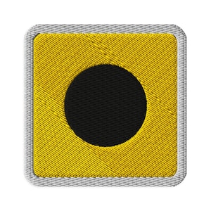 May include: A square embroidered patch featuring a bright yellow background with a solid black circle centered in the middle. The patch has rounded corners and is finished with a thick, light gray stitched border around the entire perimeter.