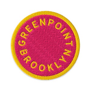 May include: Embroidered patch with a circular design. The patch features a fuchsia center with the words "GREENPOINT BROOKLYN" in yellow lettering around the edge. A yellow border surrounds the text and center.