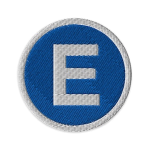 以下が含まれることがあります： 青い円形の背景に白い文字「E」が刺繍されたパッチ。パッチには白い縁取りがあり、衣類やアクセサリーへの取り付けに適しています。デザインはシンプルで大胆で、文字ははっきりと読みやすいです。