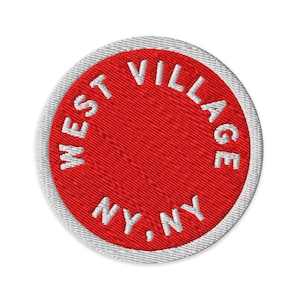 Könnte beinhalten: Ein kreisförmiger gestickter Aufnäher mit einer leuchtend roten Mitte und einem weißen Rand. Der Text WEST VILLAGE ist in Weiß entlang der oberen Kurve gestickt, und der Text NY, NY ist in Weiß entlang der unteren Kurve des roten Feldes.