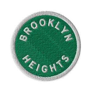 May include: Circular embroidered patch featuring the text "BROOKLYN HEIGHTS" in white, encircling a green centre. The patch has a white border and is set against a white background. The text is in a bold, sans-serif font.