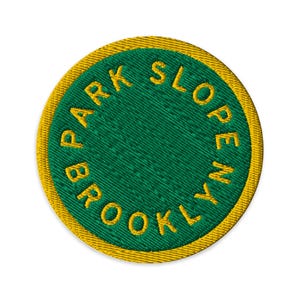 May include: Embroidered patch with the text "PARK SLOPE BROOKLYN" in gold lettering on a green background. The patch has a gold border and is circular in shape. Ideal for jackets, bags, or other fabric items.