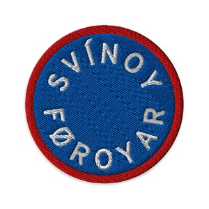 May include: Circular embroidered patch featuring the text "SVÍNOYAR FØROYAR" in white, encircling a blue centre. The patch is edged with a red border. Suitable for clothing or accessories.