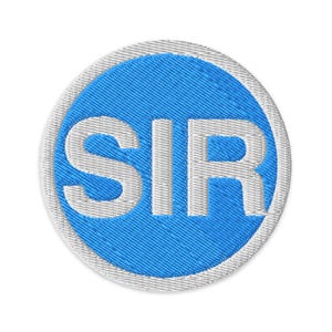 Puede incluir: Parche bordado circular con centro azul y borde blanco. El centro presenta las letras "SIR" en blanco, cosidas sobre un fondo azul texturizado. El parche tiene un borde blanco.