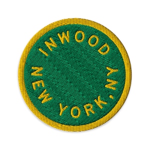 May include: A circular embroidered patch featuring a deep green center and a thick yellow border. The text INWOOD NEW YORK, NY is stitched in yellow thread in a circular pattern along the inner edge of the patch, creating a bold contrast.