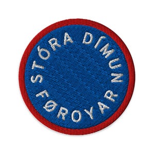 May include: Embroidered circular patch with the text "STÓRA DÍMUN FØROYAR" in white on a blue background, surrounded by a red border. The patch has a textured appearance.