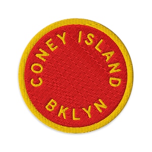 May include: Embroidered patch with a red center and a yellow border. The text "CONEY ISLAND" and "BKLYN" are embroidered in yellow, following the circular shape of the patch. The patch is round and has a textured appearance.