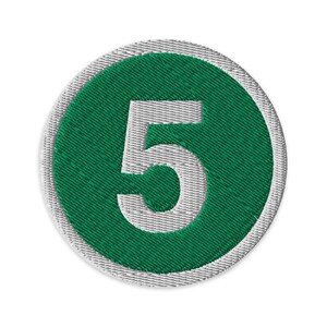 May include: Embroidered patch featuring the number 5 in white, centered on a green circle. The circle is surrounded by a gray, stitched border. The patch is circular and has a textured appearance.