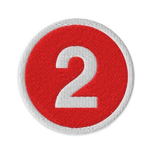 May include: Embroidered patch with the number 2 in white, set on a red circle, with a white border. The patch is circular and has a textured finish. Ideal for clothing or accessories.
