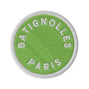 May include: A circular embroidered patch featuring a bright lime green centre with the white text BATIGNOLLES PARIS stitched in a circular pattern. The patch is finished with a thick, white embroidered border around the entire outer edge.