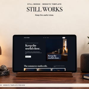 Pode incluir: Uma exibição digital do modelo de site Still Works em uma tela de tablet. A interface apresenta um tema escuro com tipografia branca, exibindo o texto Still Works e Keep the useful close, juntamente com imagens de produtos e menus.