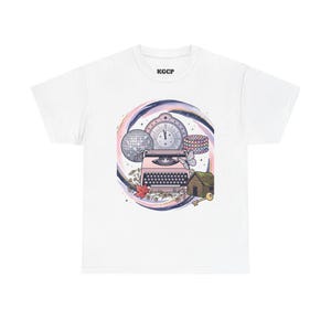 May include: White t-shirt featuring a colorful illustration. The design includes a pink typewriter, a disco ball, a clock, a house, a key, and a bracelet, all set against a swirling background. The text "KGCP" is printed on the upper part of the shirt.