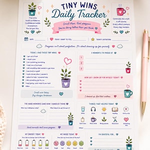May include: A white paper daily tracker sheet titled Tiny Wins Daily Tracker with colorful illustrations of potted plants and mugs. The layout includes sections for date, intentions, mood, energy, gratitude, and reflections with various heart icons.