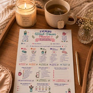 May include: A wooden tray holds a lit candle, a mug of tea, and a planner titled "Evening Wind-Down Planner." The candle has the words "Breathe, Relax, Unwind." A gold pen rests on the planner, and a sleep mask is visible.