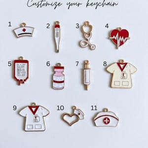 May include: A collection of eleven medical-themed metal charms for a keychain, labelled 1 through 11. The charms feature designs including a nurse cap, thermometer, stethoscope, heart with EKG line, blood bag, vial, syringe, and scrub tops.