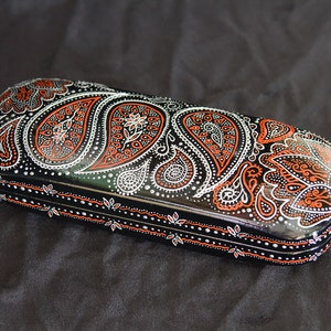 Eyeglass case for small glasses, hand-painted with red and silver paisley design. View from the side, to show the design on sides