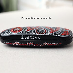 Eyeglasses case, hand-painted with red and silver paisley design. Example of personalization with the name painted on the front of the case. Close-up view from the side.