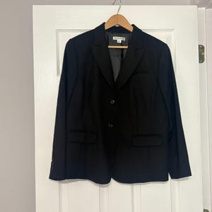 May include: A black blazer with a two-button closure, two front pockets, and a notched lapel. The blazer is hanging on a wooden hanger. The brand name "PENDLETON" is visible on the label.