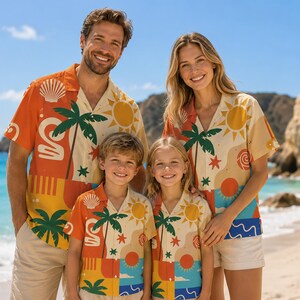 May include: Matching short-sleeved button-down shirts featuring a vibrant tropical print with palm trees, suns, seashells, and abstract shapes in shades of orange, yellow, blue, and cream, worn with light-colored shorts on a sunny beach.